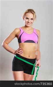 Weight loss, slim body, healthy lifestyle concept. Fit fitness woman in sportswear measuring her hips with green measure tape. Fit woman measuring her hips with measure tape