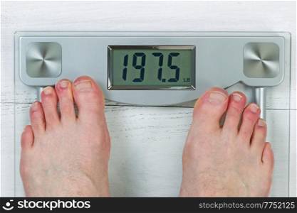Weight scale, displaying body weight, with bare male feet