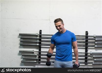 weight training fitness man inside working out arms lifting dumbbells doing biceps curls. Male sports model exercising indoors as part of healthy lifestyle.