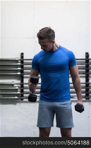 weight training fitness man inside working out arms lifting dumbbells doing biceps curls. Male sports model exercising indoors as part of healthy lifestyle.