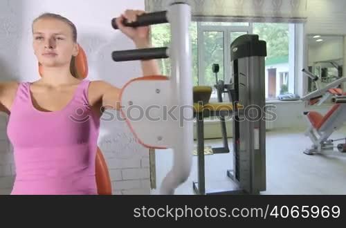 Weight training workout on exercise chest fly machine in health fitness club pan shot