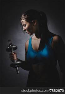 Weightlifting, young woman wearing sportswear and she excercise, studio shot, dark background