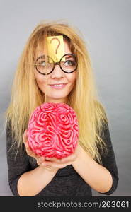 Weird blonde woman holding brain having something on mind, thinking of idea.. Weird woman holding brain having idea