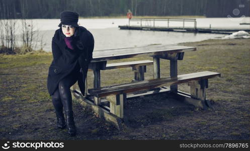 Weird fashion woman wearing a winter coat and hat and she posing in a wintry beach, cold rainy weather, cross processed image