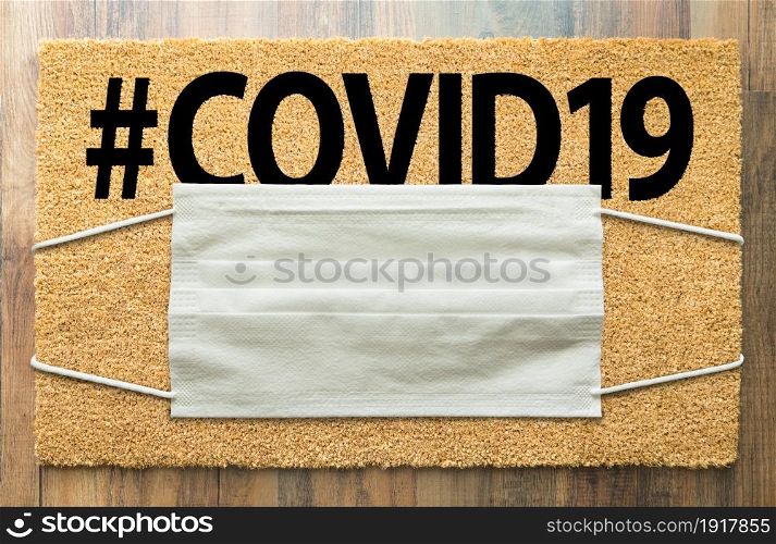 Welcome Mat With Medical Face Mask and #COVID19 Text Amidst The Coronavirus Pandemic.