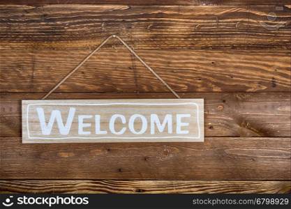 Welcome poster hung on a rustic wooden wall