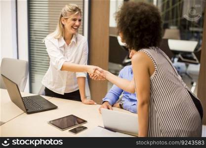 Welcoming business woman giving a handshake and smiling in moden office
