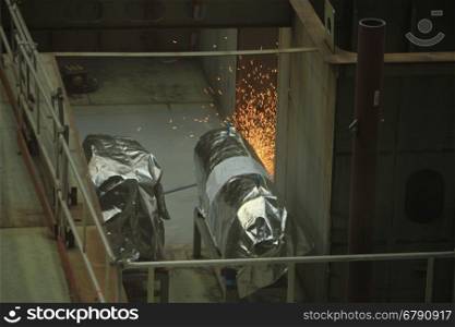 Welder at work in a shipyard, heavy industry