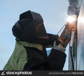 Welder at work on the background of blue sky