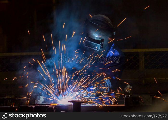 welder is welding assembly car parts in factory with protection mask