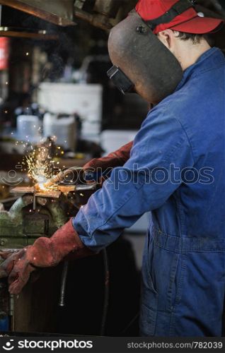 welder is welding metal part in garage. with protective mask, industrial steel welder work. welder is welding metal part in garage. with protective mask, industrial steel welder