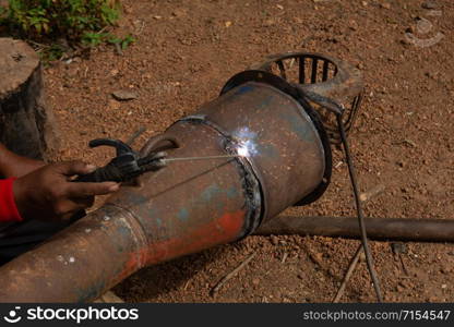 Welder is welding metal piping in construction site