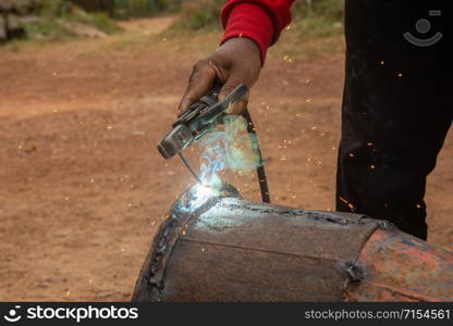 Welder is welding metal piping in construction site