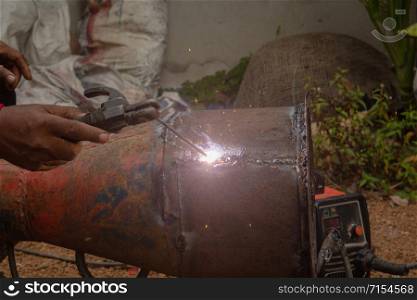Welder is welding metal piping in construction site