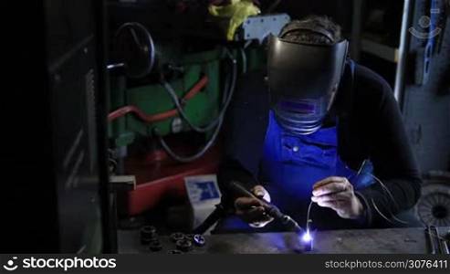Welder man Tig welding in workshop. Manual worker welding metal tool.
