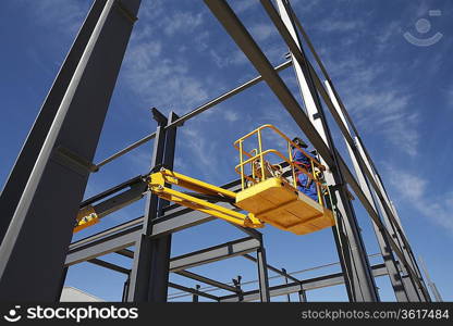 Welder working from cherry picker on warehouse construction