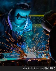 Welders team welding automotive part in assembly line