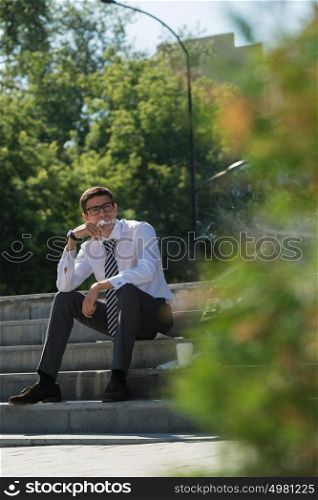 Well dressed business man smoking sitting on a street sidewalk