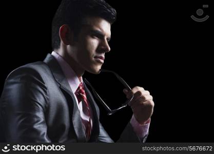 Well-dressed businessman with glasses against black background
