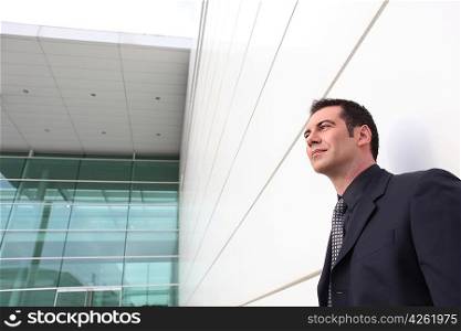 well dressed man leaning against a modern building