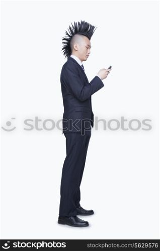Well-dressed young man with Mohawk using mobile phone