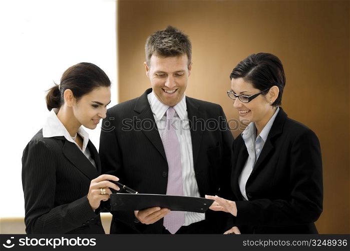 Well dresses business people talking and looking at a file in font of an executive wooden backgrond.