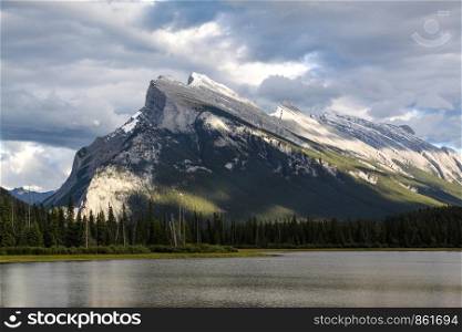 Well-known mountain on lake towers in cloudy sky