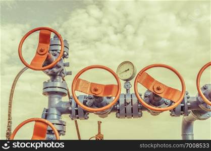 Wellhead with valve armature on a oilfield. Oil and gas industry concept. Industrial site background. Extraction of oil. Toned sepia.. Wellheads with valve armature on a oil field.