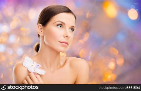 wellness and beauty concept - beautiful bare woman with orchid flower over holidays lights background. woman with orchid flower over green background. woman with orchid flower over green background