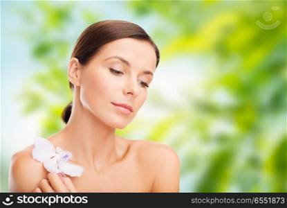 wellness and beauty concept - beautiful woman with orchid flower over green natural background. woman with orchid flower over green background. woman with orchid flower over green background