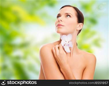 wellness and beauty concept - beautiful woman with orchid flower over green natural background. woman with orchid flower over green background. woman with orchid flower over green background