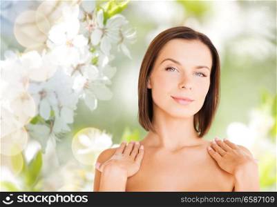wellness and beauty concept - portrait of beautiful bare woman over natural cherry blossom background. beautiful bare woman over green natural background