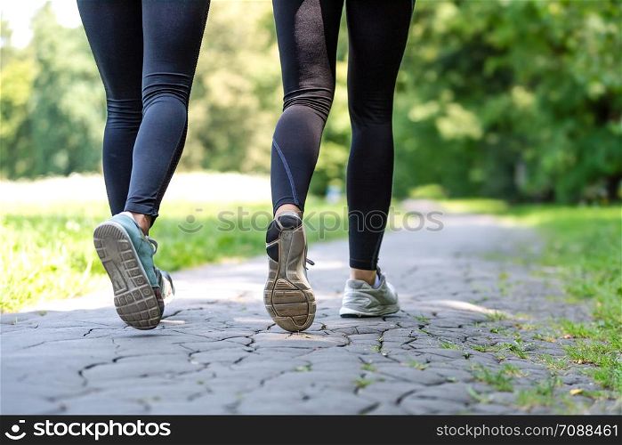 Wellness and fitness concept - low angle view of running women in the park on a sunny morning.