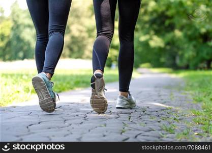 Wellness and fitness concept - low angle view of running women in the park on a sunny morning.