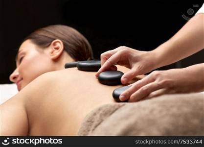 wellness, beauty and bodycare concept - close up of woman having hot stone massage at spa. close up of woman having hot stone massage at spa