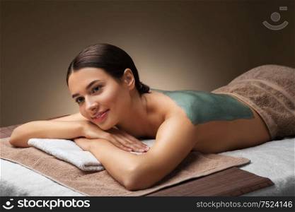 wellness, beauty and cosmetology concept - beautiful young woman lying with blue clay mask at spa. woman with blue clay mask in spa