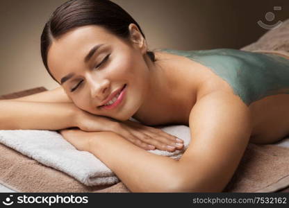 wellness, beauty and cosmetology concept - beautiful young woman lying with blue clay mask at spa. woman with blue clay mask in spa