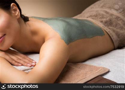 wellness, beauty and cosmetology concept - beautiful young woman lying with blue clay mask at spa. woman with blue clay mask in spa