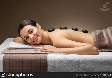 wellness, beauty and relaxation concept - beautiful smiling young woman having hot stone massage at spa. smiling woman having hot stone massage at spa