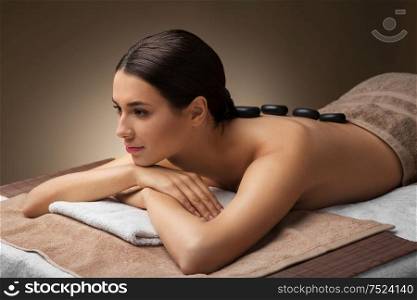 wellness, beauty and relaxation concept - beautiful young woman having hot stone massage at spa. woman having hot stone massage at spa