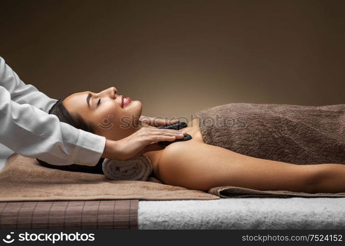 wellness, beauty and relaxation concept - beautiful young woman having hot stone massage at spa. beautiful woman having hot stone massage at spa