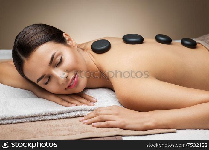 wellness, beauty and relaxation concept - beautiful young woman having hot stone massage at spa. woman having hot stone massage at spa