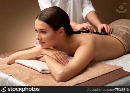 wellness, beauty and relaxation concept - beautiful young woman having hot stone massage at spa. beautiful woman having hot stone massage at spa