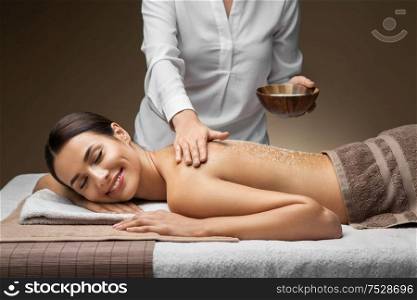 wellness, beauty and relaxation concept - beautiful young woman having salt massage at spa. beautiful young woman having salt massage at spa