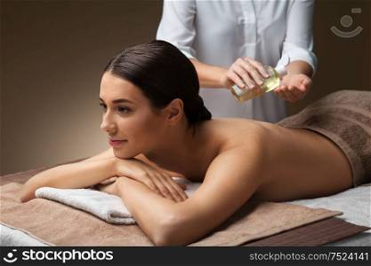 wellness, beauty and relaxation concept - beautiful young woman lying and having back massage with oil at spa. beautiful woman having back massage at spa