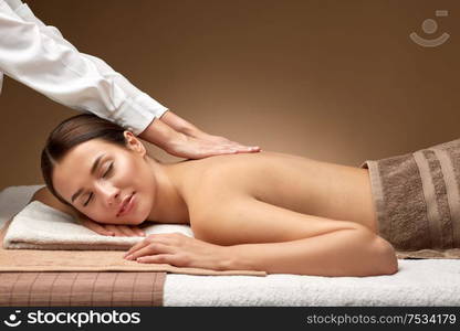 wellness, beauty and relaxation concept - beautiful young woman lying and having back massage at spa. woman lying and having back massage at spa