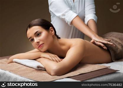 wellness, beauty and relaxation concept - beautiful young woman lying and having back massage at spa. woman lying and having back massage at spa