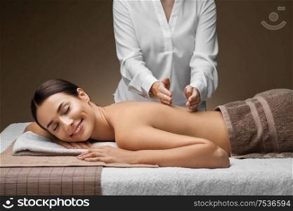 wellness, beauty and relaxation concept - beautiful young woman lying and having back massage at spa. woman lying and having back massage at spa