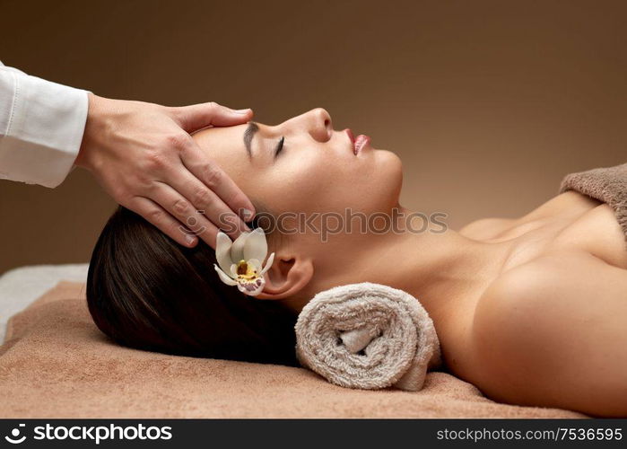 wellness, beauty and relaxation concept - beautiful young woman lying with closed eyes and having face and head massage at spa. woman having face and head massage at spa