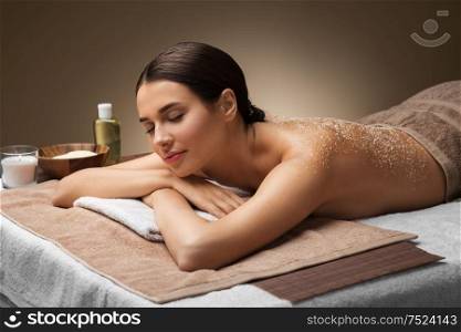 wellness, beauty and relaxation concept - beautiful young woman lying with sea salt on skin at spa. woman lying with sea salt on skin at spa